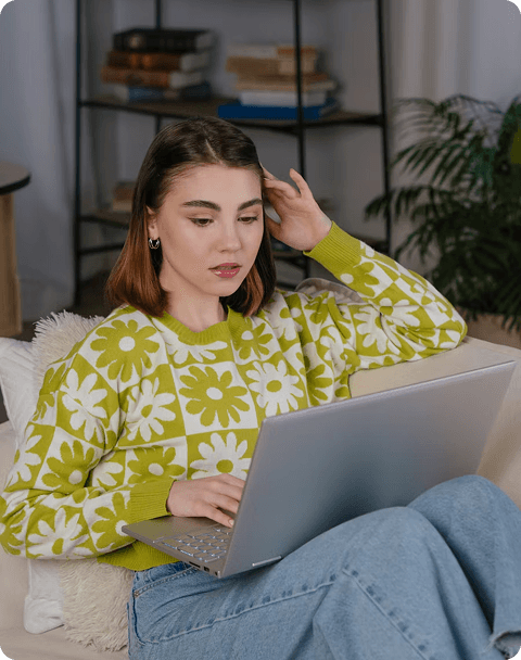 A young woman sitting on a couch working on a laptop