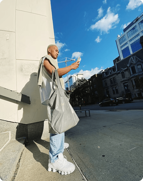 A young man standing outside looking at his phone